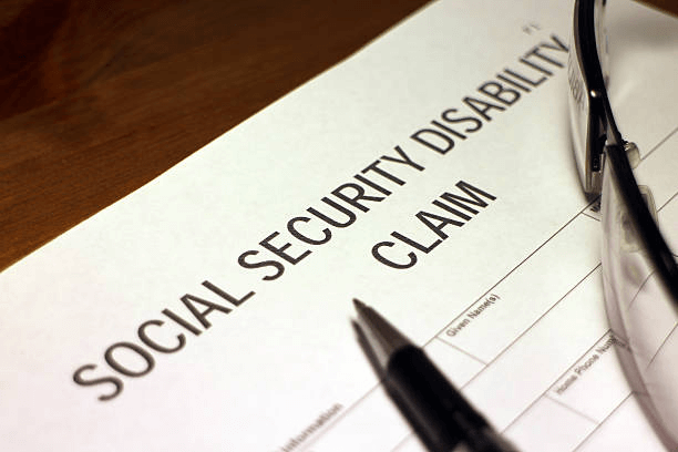 A Social Security Disability claim form with a pen lying on top of it.